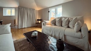 A modern living room with a sofa, a coffee table, and a lamp. - Grand 2BR Penthouse | 100" Cinema | Hyde Park (London)