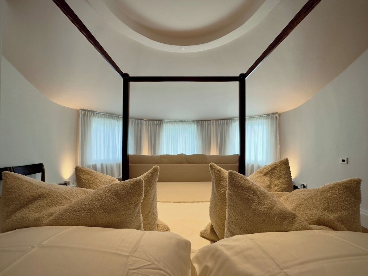 Une chambre à coucher avec un grand lit, deux tables de chevet et une fenêtre avec des rideaux.
