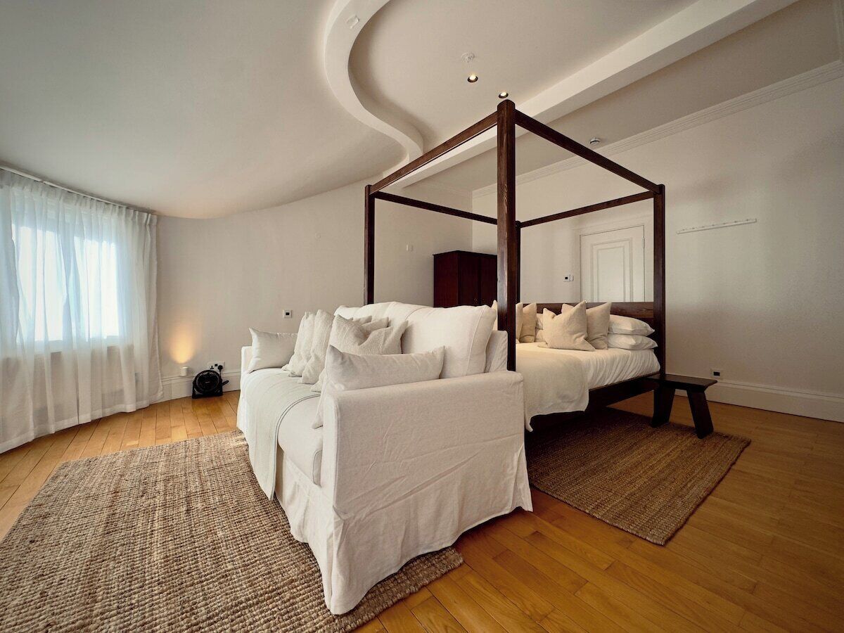 A bedroom with a four-poster bed, a sofa, and a small table.