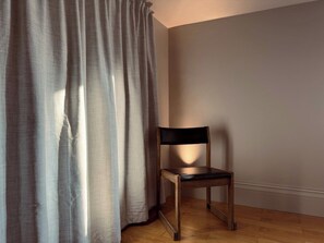 Ein Stuhl in einem Raum mit Holzboden und schlichter Wand.