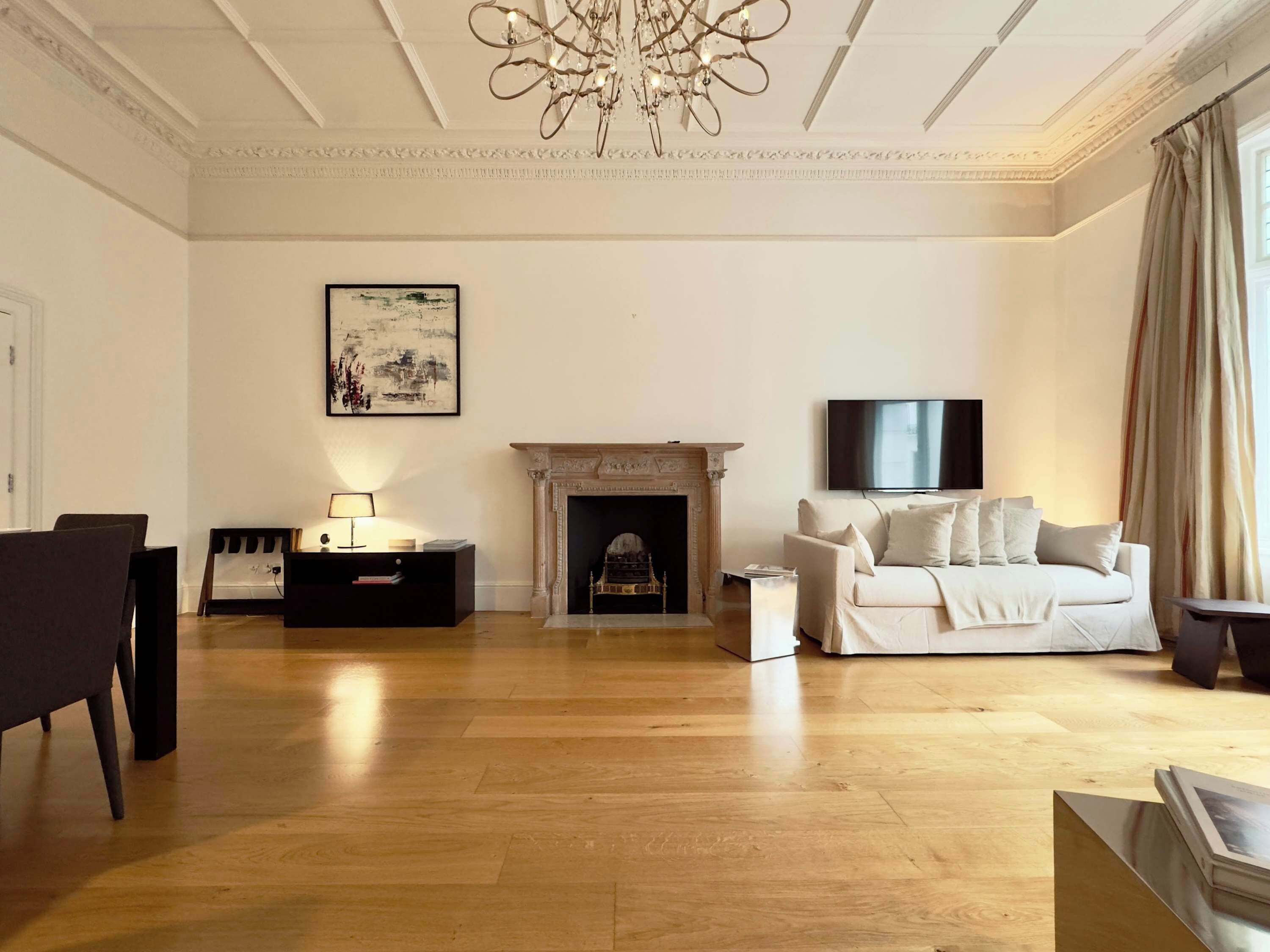 A living room with a fireplace, a sofa, a TV, and a chandelier.