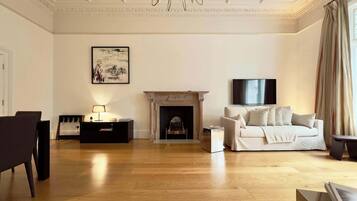 A living room with a fireplace, a sofa, a TV, and a chandelier.