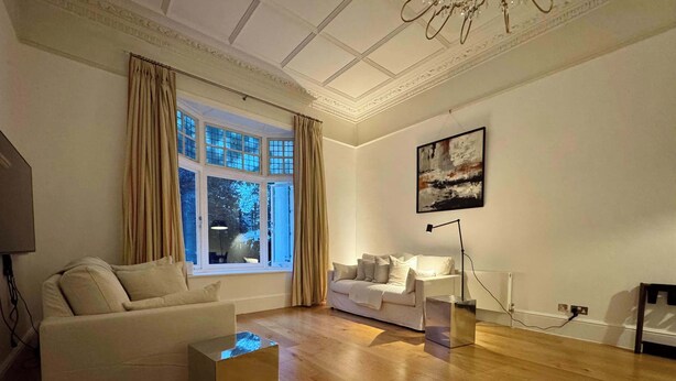 Ein modernes Wohnzimmer mit einer Couch, einem Couchtisch, einer Lampe und einem Bild an der Wand.