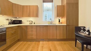 Eine moderne Küche mit Holzausstattung, einer Mikrowelle, einem Wasserkocher und einem Spülbecken.