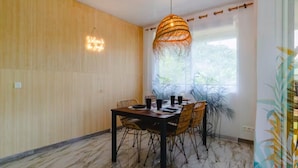 A dining area with a wooden wall, a marble floor, a table with chairs, and a hanging light fixture. - Tropical Moorea Escape, 3BR, A/C, Strong WiFi & Mountain Views (Moorea-Maiao)