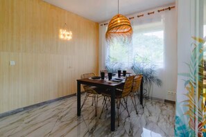 Ein Essbereich mit Holzwand, Marmorboden, Tisch und Stühlen sowie einer Pendelleuchte.