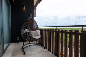 A balcony with a hanging chair, a railing, and a view of greenery. - Luxury 2 BR PH w/Private Pool, Walk to Beach (Tulum)