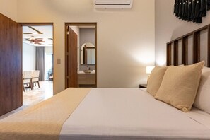 A hotel room with a bed, bedside table, and a view of a bathroom. - Luxury 2 BR PH w/Private Pool, Walk to Beach (Tulum)