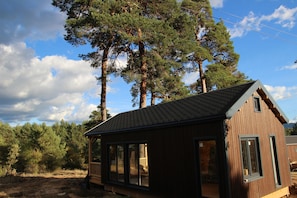 A cabin with a sloped roof, large windows, and a deck area. - Costa Oxígeno (Quintanar de la Sierra)
