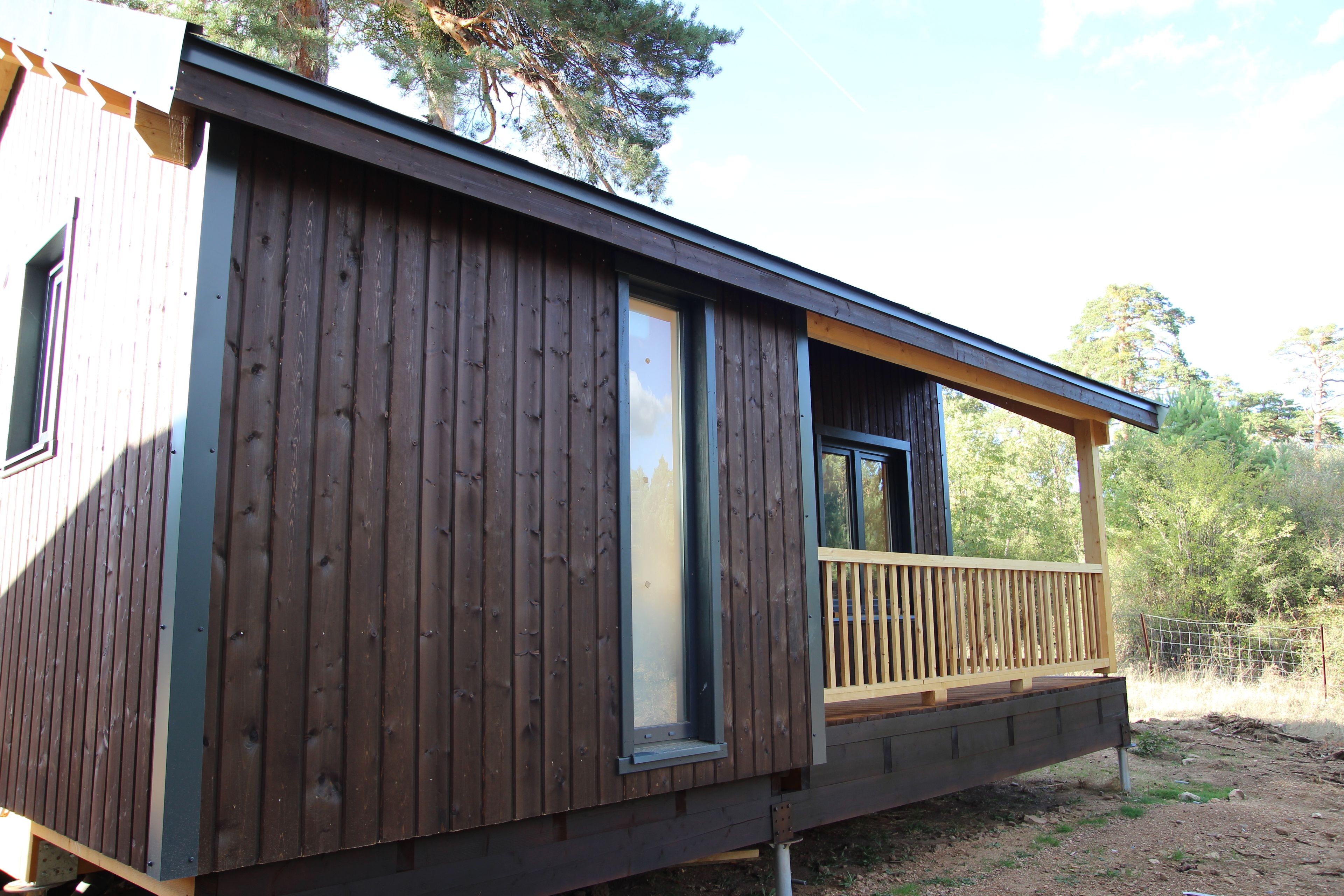 A wooden cabin with a balcony and a large window.