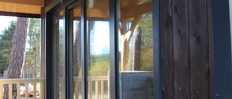 A wooden cabin with a covered porch and a large window.