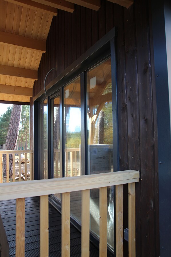 A wooden cabin with a covered porch and a large window. - Costa Oxígeno (Quintanar de la Sierra)