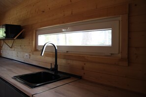 A kitchen with a black sink, wooden walls, and a window above the sink.