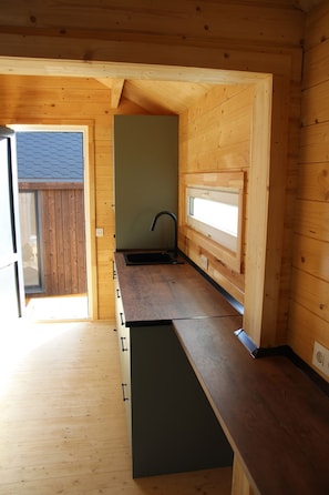 A compact kitchen with wooden walls, a built-in sink, and a window. - Costa Oxígeno (Quintanar de la Sierra)