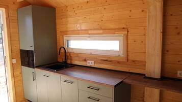A compact kitchen with a built-in sink, a window above the countertop, and wooden cabinetry.