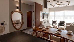 A modern dining area with a wooden table set for four, a large mirror, and a television mounted on the wall. - Luxury 2BR w/Rooftop Pool & Gym I Walk to Beach (Tulum)