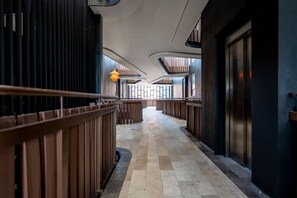 A corridor with a checkered floor, wooden railings, and a curved ceiling. - Luxury 2BR w/Rooftop Pool & Gym I Walk to Beach (Tulum)