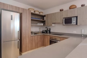 A modern kitchen with wooden cabinets, a stainless steel refrigerator, a microwave, and a coffee maker. - Relaxing 2BR Oasis w/ Pool & Balcony | Sleeps 6 (Tulum)