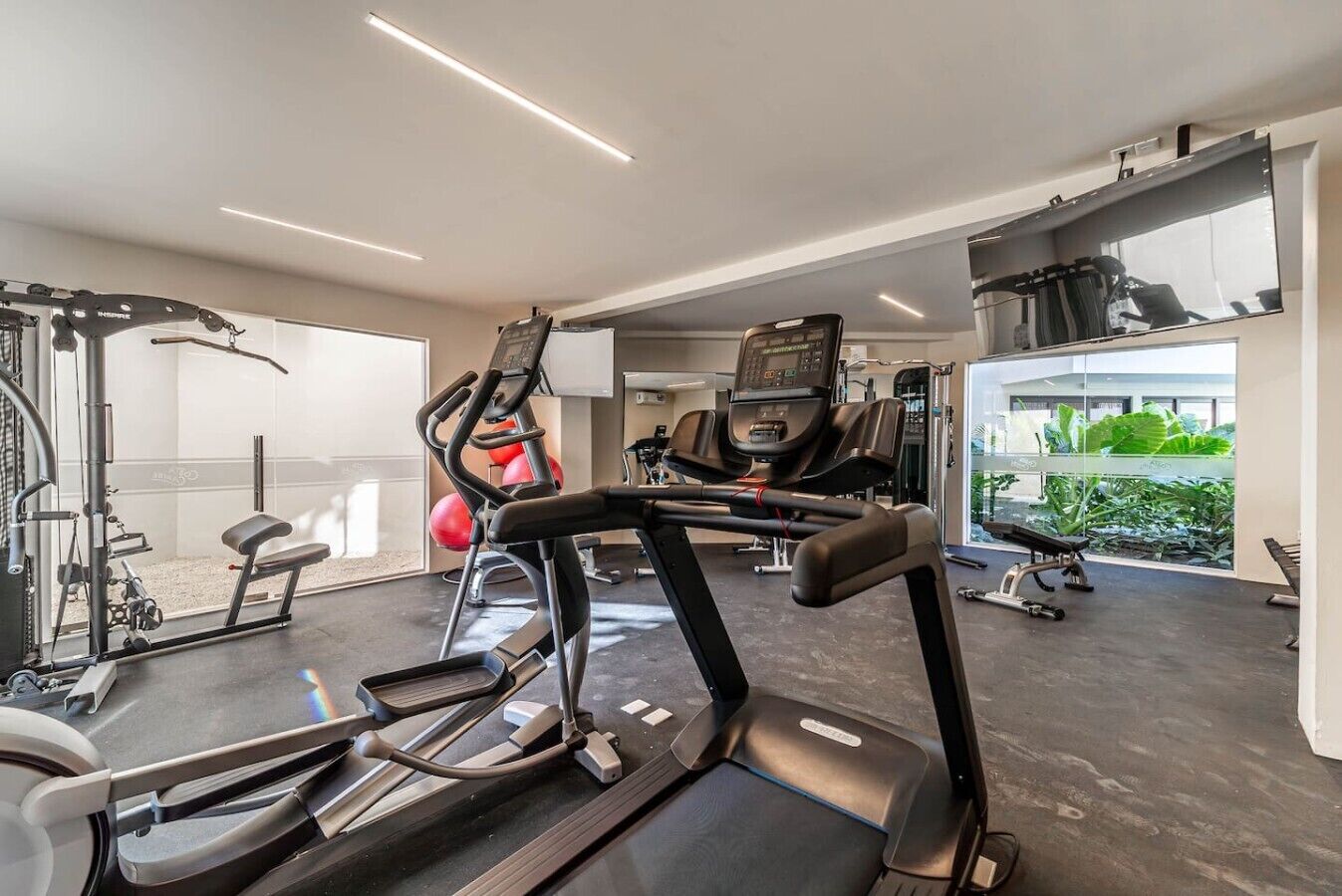 Ein Fitnessstudio mit Laufbändern, Gymbällen und Krafttrainingsgeräten.