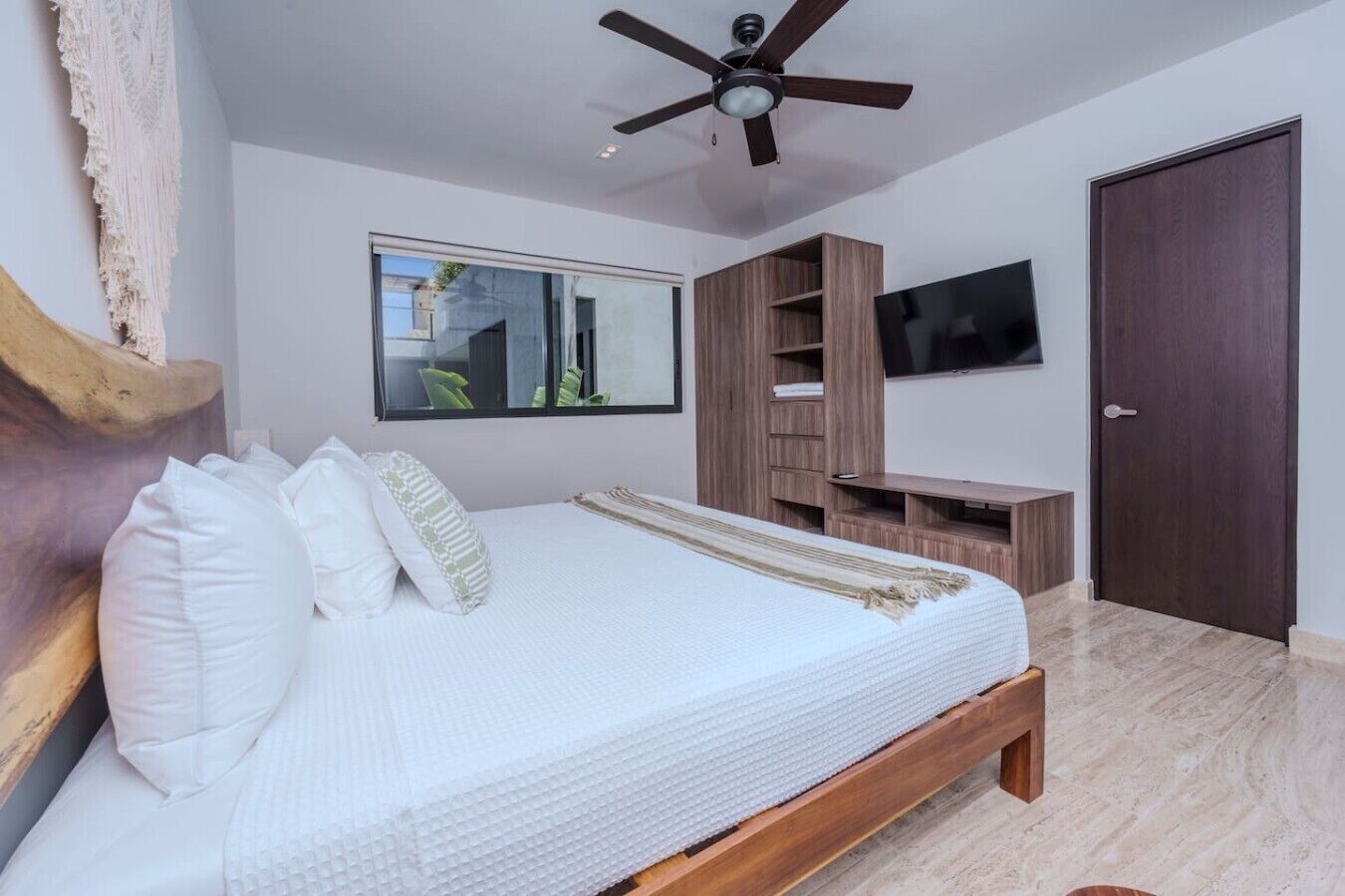 A bedroom with a bed, a ceiling fan, a TV, and a wardrobe.