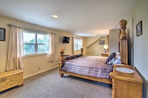 A bedroom with a large bed, a television, a wooden dresser, and a window with curtains. - Coos Bay Farmhouse Near Ocean, Pet-Friendly (Coos Bay)