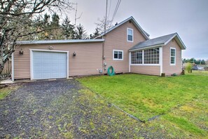 A two-story house with a garage, a covered porch, and a well-maintained lawn. - Coos Bay Farmhouse Near Ocean, Pet-Friendly (Coos Bay)