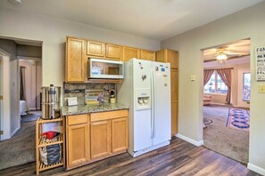 A compact kitchen with wooden cabinets, a microwave, and a refrigerator. - Coos Bay Farmhouse Near Ocean, Pet-Friendly (Coos Bay)