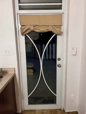 A white door with a glass panel, a metal handle, and a beige curtain. - Azul Beach Apartments, Apt. 1: A Cozy Apartment Just Steps from the Beach… (Boquerón)