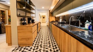 A modern kitchen with wooden cabinets, a black marble countertop, and a patterned floor.