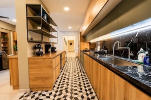 A modern kitchen with wooden cabinets, a black marble countertop, and a patterned floor. - Villa Koï - 4 bedrooms - pool - Terres Basses (terres basses)