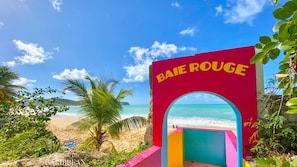 A colorful archway with 'BAIE ROUGE' written on it, leading to a beach with clear blue water and a palm tree. - Villa Koï - 4 bedrooms - pool - Terres Basses (terres basses)