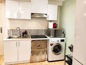 A compact kitchen with white cabinets, a microwave, a washing machine, and a sink. - Elegant and cozy studio apartment in the historic center of Hyères (Hyères)