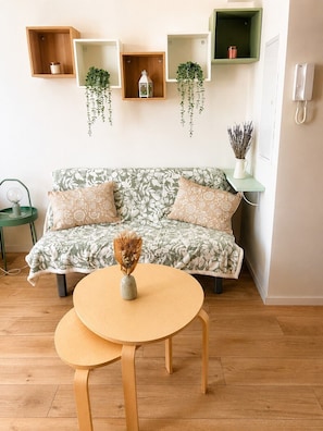 Ein Wohnzimmer mit einer Couch, zwei runden Tischen und Regalen mit Pflanzen.