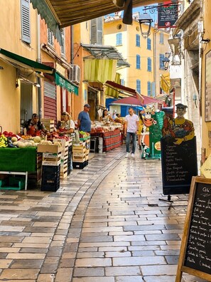 A bustling outdoor market with vendors selling fruits and vegetables. - Elegant and cozy studio apartment in the historic center of Hy ères (Hyères)