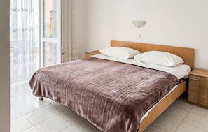 Ein Bett mit einem hölzernen Kopfstück, weißen Kissen und einer braunen Decke.