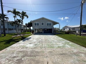A two-story house with a covered porch and a driveway leading to the front door. - Waterfront 2 Bed 2 Bath home, Boat Lift, Trailer Parking, 2 Kayaks and 2 Bikes (Saint James City)