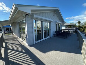Um deck coberto com guarda-corpo, uma área de varanda coberta com cadeiras, e vista para a paisagem ao redor.