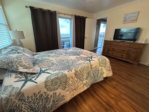 Quarto com cama, penteadeira, televisão e vista para o exterior.