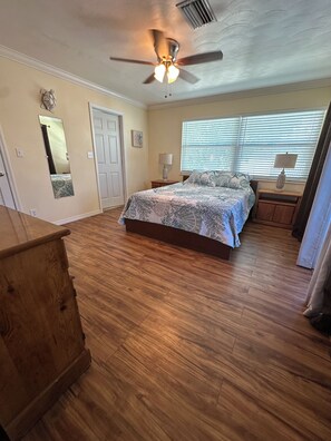 A bedroom with a bed, wooden floor, ceiling fan, and a window with blinds. - Waterfront 2 Bed 2 Bath home, Boat Lift, Trailer Parking, 2 Kayaks and 2 Bikes (Saint James City)