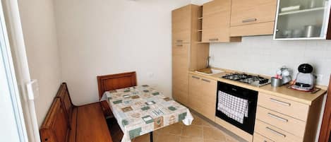 Una cocina compacta con una mesa de comedor, armarios de madera, estufa y lavavajillas.