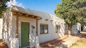 A single-story building with a green door, numbered 18, and a small porch with a wooden beam. - El Colorado Casita 18 (Manitou Springs)
