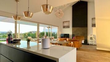 Una cocina moderna con una isla grande, iluminación colgante y vistas al exterior.