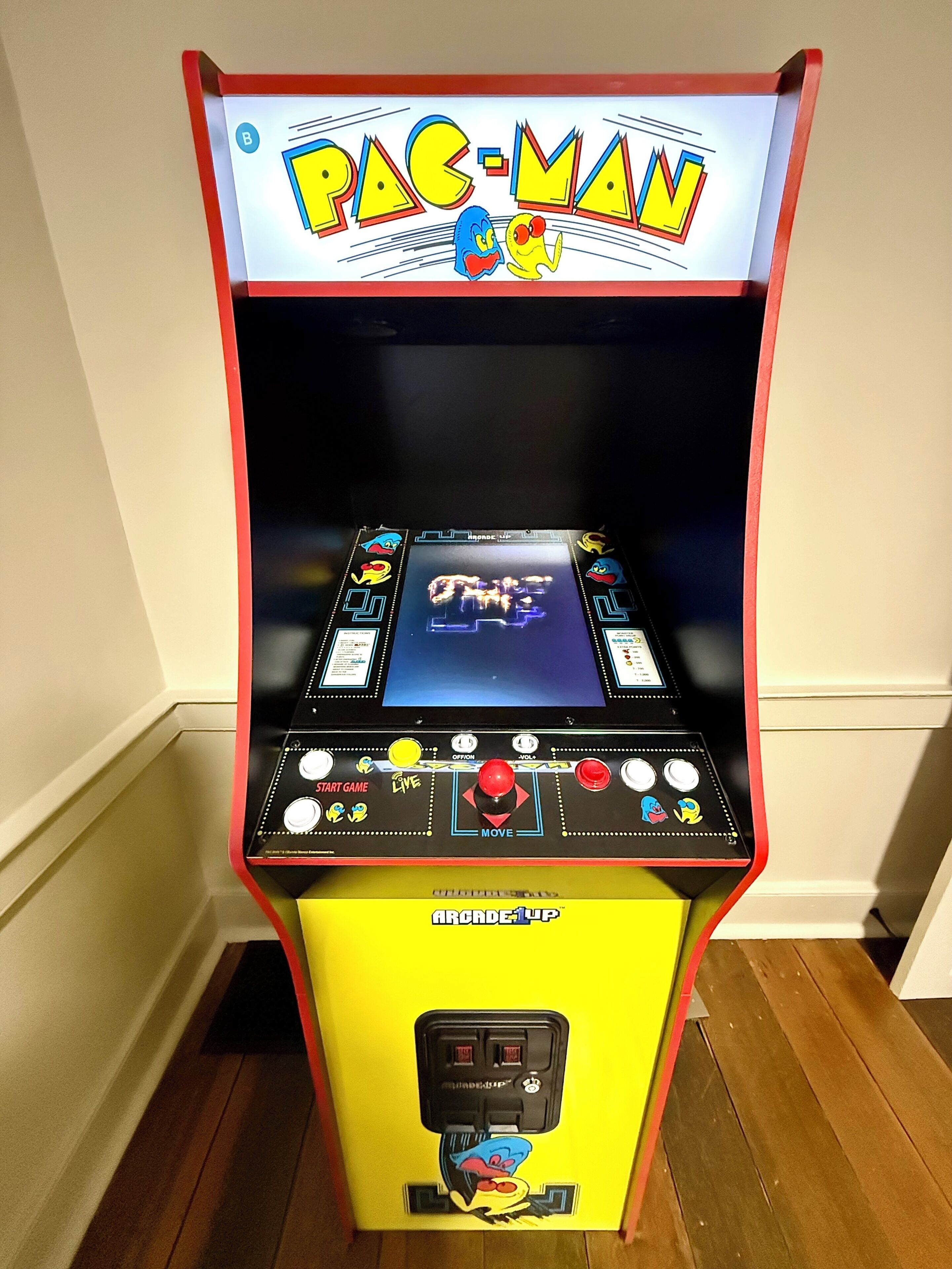 Una máquina arcade de Pac-Man con base amarilla, una pantalla mostrando el juego y botones de control.