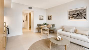A modern living room with a sofa, a round coffee table, and a dining area with chairs and a table.