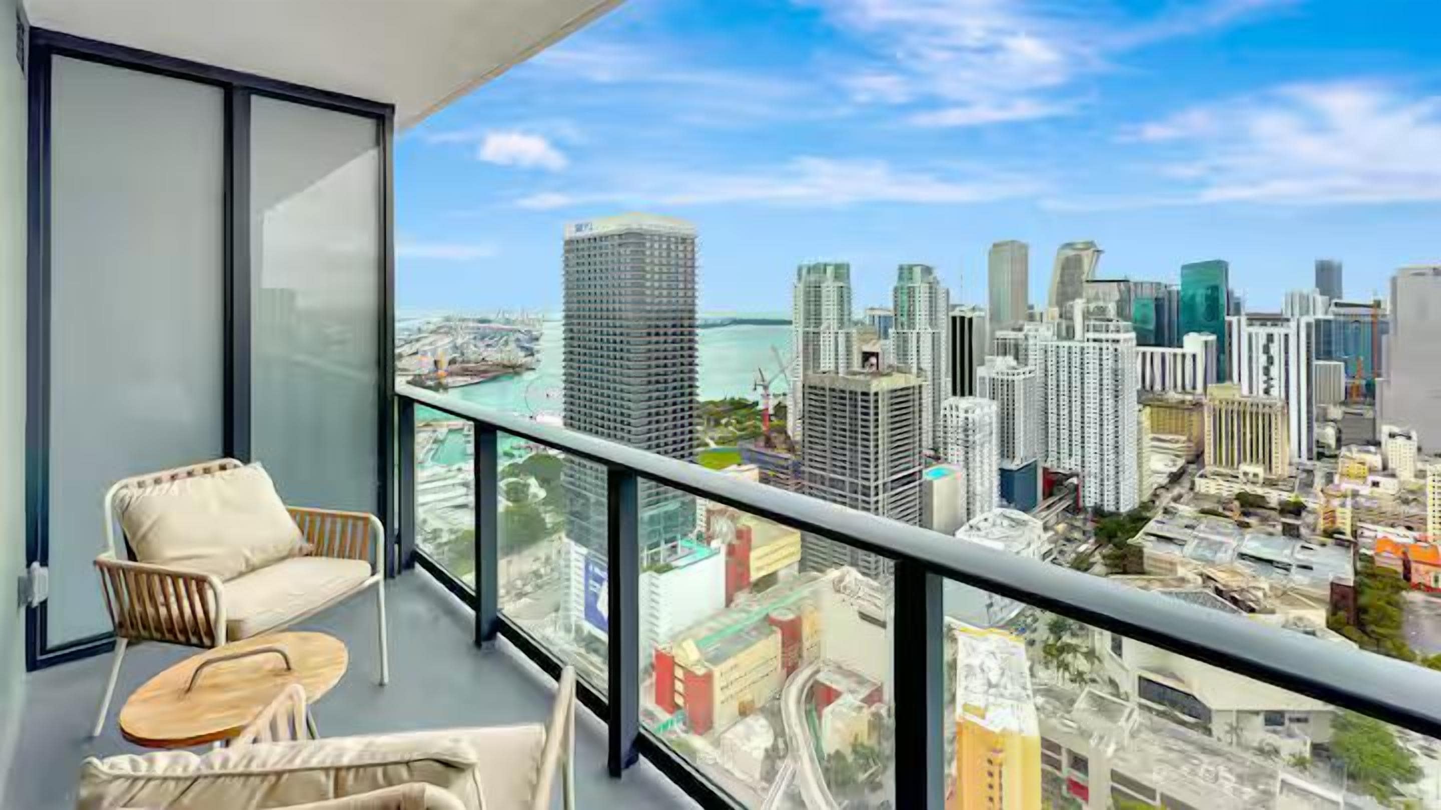 A balcony with a city view, a chair, and a small table.