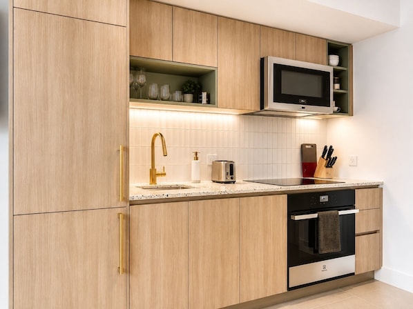 A modern kitchen with wooden cabinets, a stainless steel microwave, a toaster, and a dishwasher.