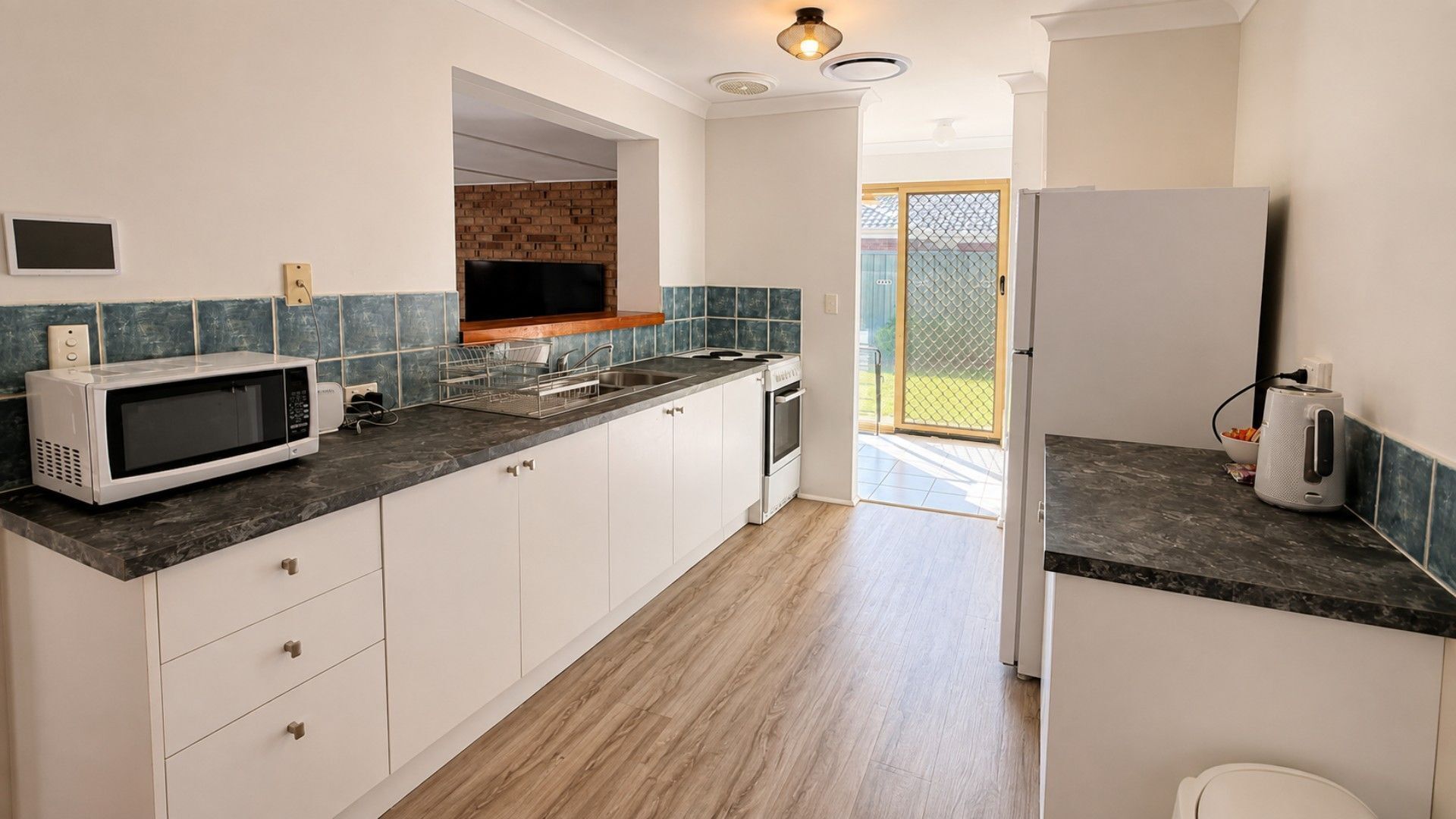 Une cuisine moderne avec des meubles blancs, un four à micro-ondes, une cuisinière et un réfrigérateur.