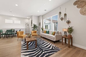Un salon spacieux comprenant un canapé, des fauteuils, une table basse et un coin repas avec des chaises et une table.