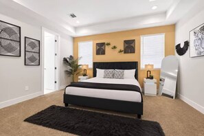 A bedroom with a bed, bedside tables, wall art, and a large window. - Cozy Northside home ~20 mins to downtown Houston (Houston)
