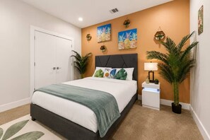 Une chambre à coucher avec un lit, une table de chevet, une lampe et des œuvres d’art murales.